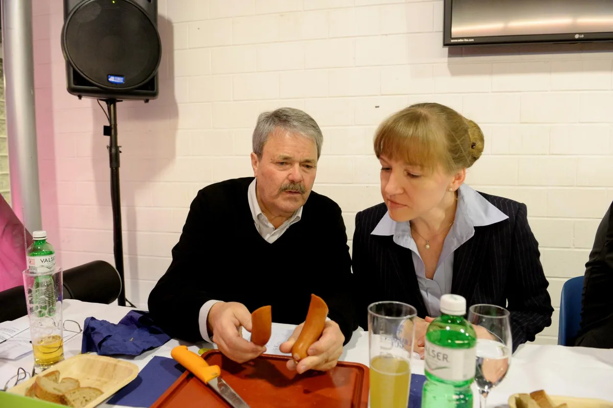 Mann und Frau sitzen an einem Tisch und degustieren Würste.